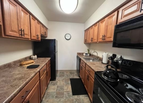 a kitchen with a stove top oven next to a refrigerator at Monroeville Apartments, Monroeville, PA