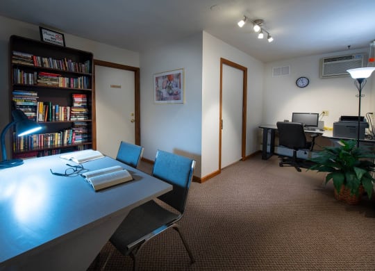 a room with a table and chairs and a bookcase filled with books at Monroeville Apartments, Pennslyvania, 15146