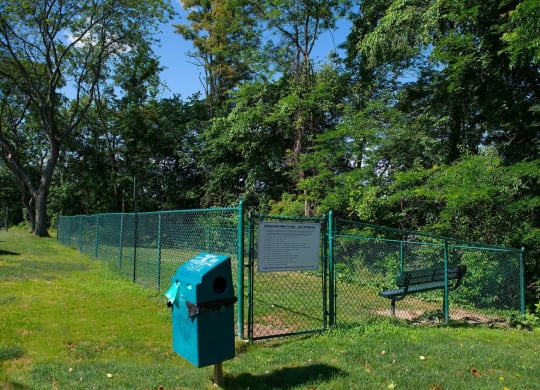 a park bench next to a fence with a sign on it at Monroeville Apartments, Pennslyvania