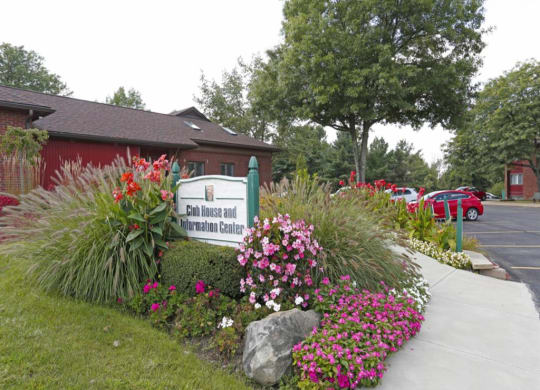 a building with a sign and flowers in front of it at Monroeville Apartments, Monroeville, Pennslyvania