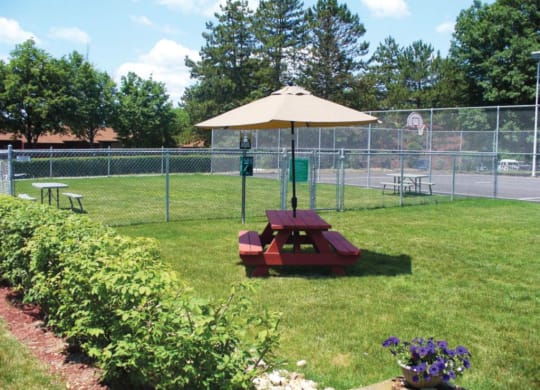 a picnic table with an umbrella in a park at Monroeville Apartments, Monroeville, PA