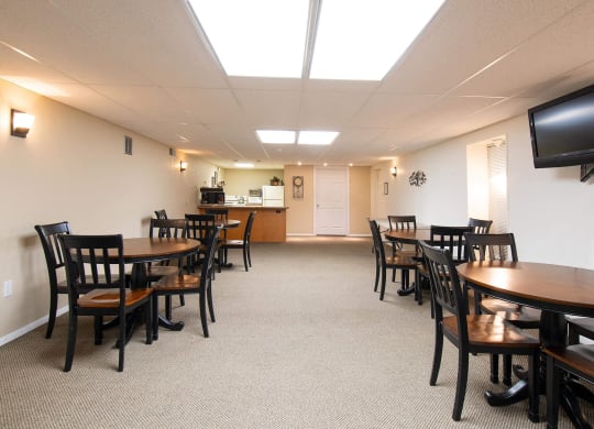 a dining room with tables and chairs and a kitchen in the background at Monroeville Apartments, Monroeville, PA, 15146