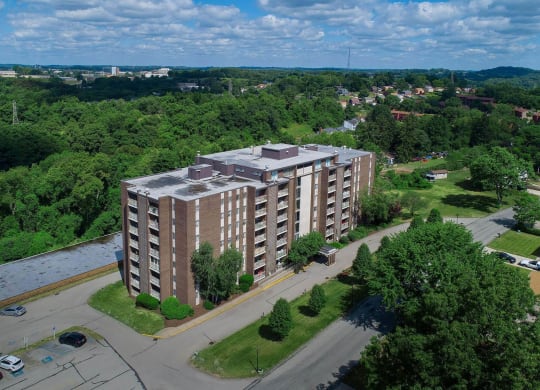 an aerial view of a large apartment building with a river and trees in the background at Monroeville Apartments, Monroeville
