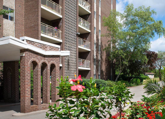 a large brick building with a courtyard and flowers in front of it at Monroeville Apartments, Monroeville, PA, 15146