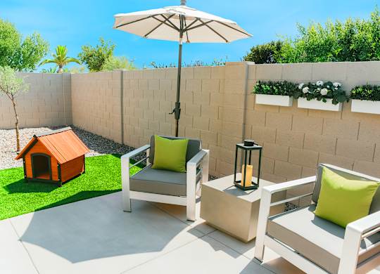 A patio with two chairs and a table with a lantern on it.
