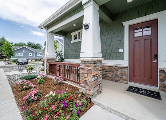 A house with a red door and a flower bed in front.
