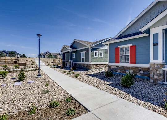 a row of blue houses with red doors and a sidewalk