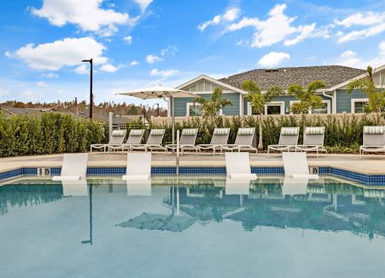 a swimming pool with lounge chairs and a house in the background