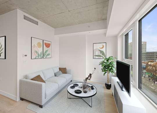 A living room with a white couch, a coffee table, and a flat screen TV.