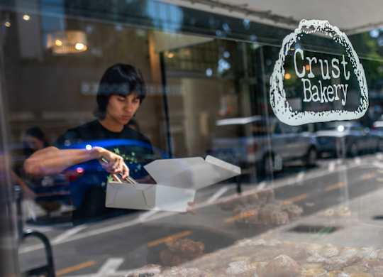 A person is placing baked goods in a box inside a bakery.