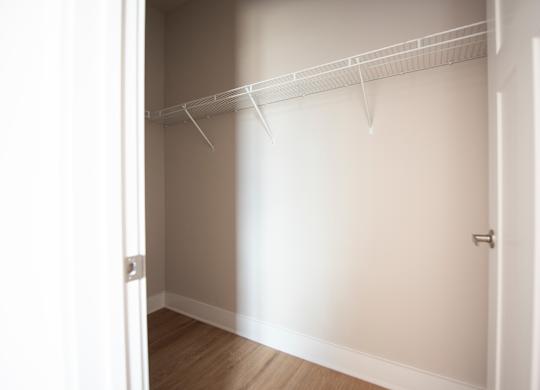 A white closet with a door and a shelf.