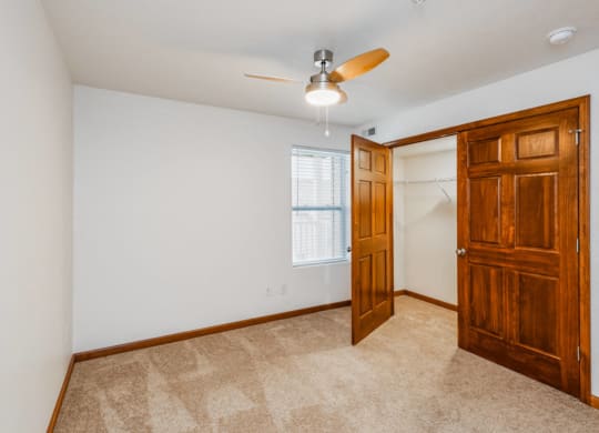 an empty bedroom with a closet and a ceiling fan