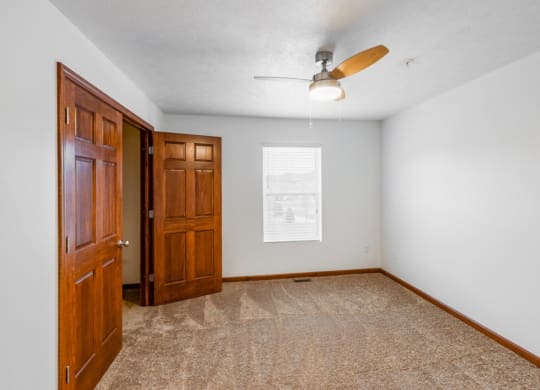 an empty room with a door and a ceiling fan