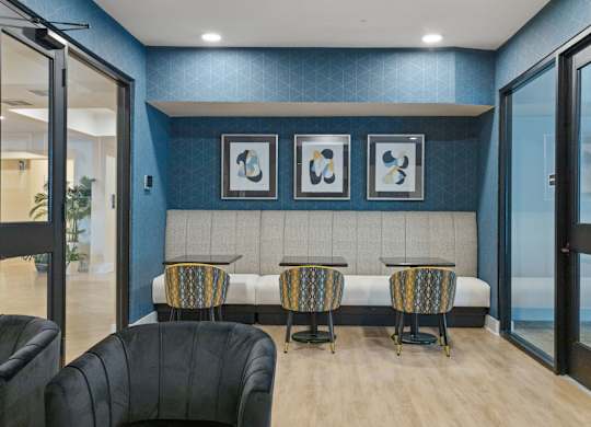 A room with a blue wall and a bench with three chairs.