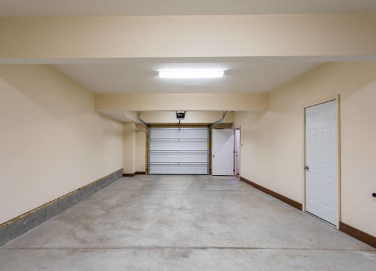 the inside of a garage with a white door and a concrete floor