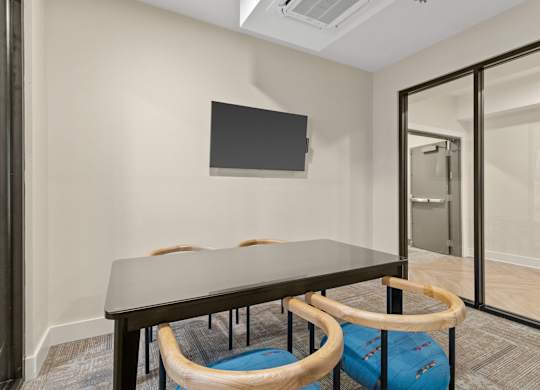 A conference room with a table, chairs, and a television on the wall.