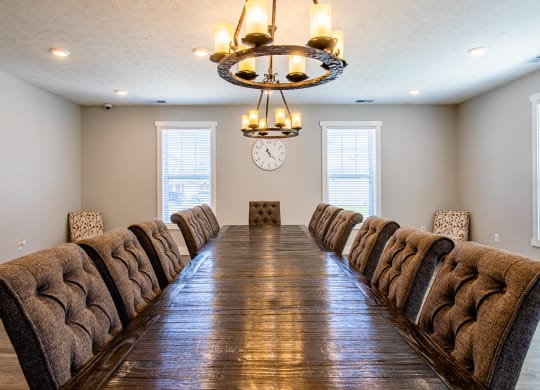 a long dining room table with chairs and a clock on the wall