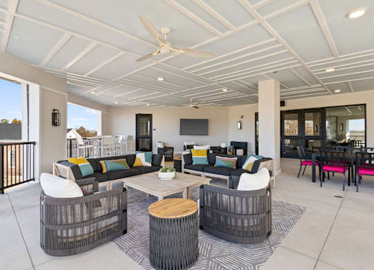A modern outdoor living space with a white ceiling fan and a black and white striped rug.