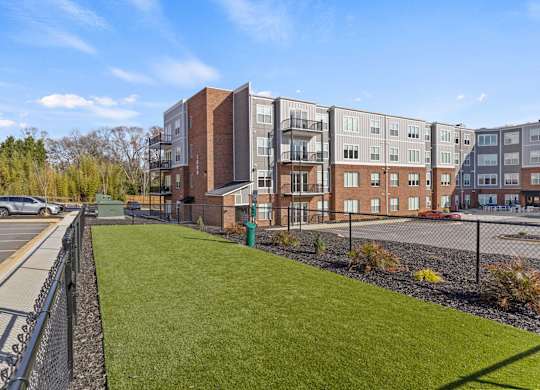 A parking lot is in front of a building with a green lawn.