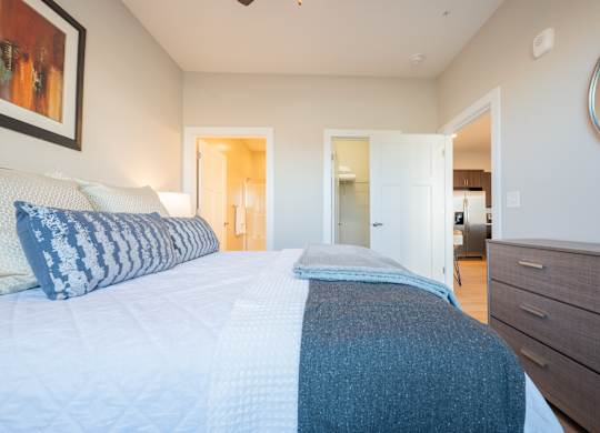 A bedroom with a large bed and a painting on the wall.