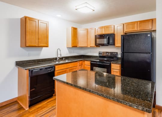 a kitchen with an island and black appliances and wooden cabinets