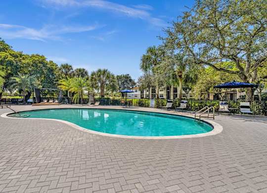 A swimming pool surrounded by a brick patio and trees.