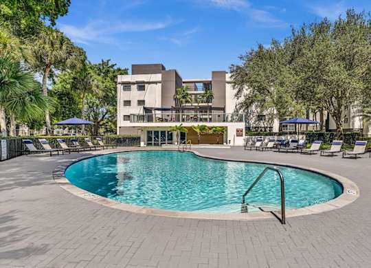 A swimming pool surrounded by a brick patio and lounge chairs.