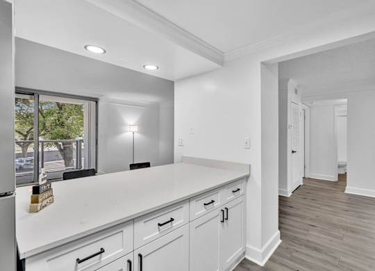 A kitchen with white cabinets and a white counter top.
