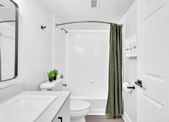 A white bathroom with a green curtain.
