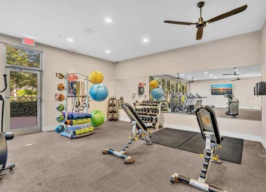 A gym with a variety of equipment including weights and exercise balls.