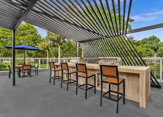 A patio with a bar and chairs under a striped awning.