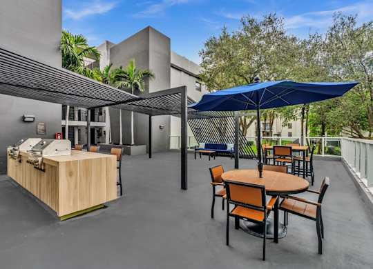 A patio with a table and chairs and a blue umbrella.