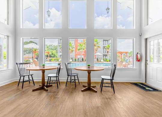 A dining room with a table and chairs in front of a large window.