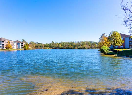 A serene lake with a row of buildings in the background.