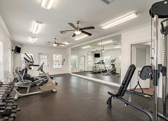 A spacious home gym with a variety of equipment including treadmills, weights, and a mirrored wall.