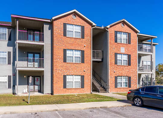 A two-story apartment building with a car parked in front.