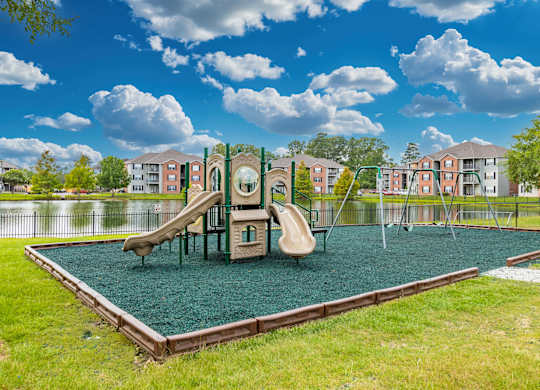 A playground with a green slide and a brown swing set.
