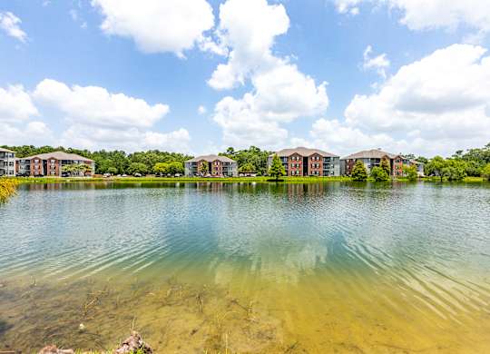 A serene lake with buildings in the background under a clear sky.