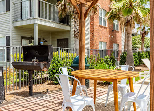 A patio with a table, chairs, and a grill.