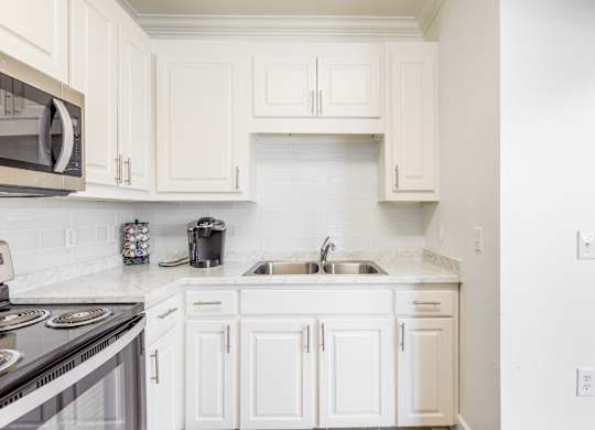A kitchen with white cabinets and a black stove top.