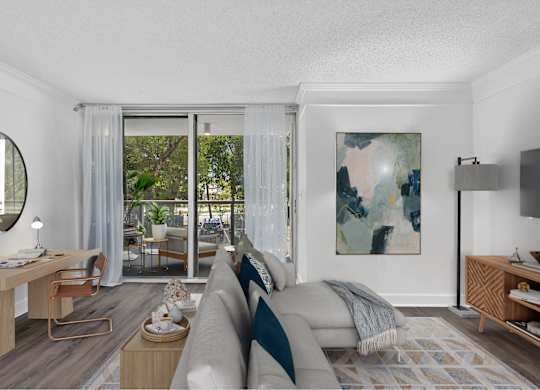 A modern living room with a grey couch and a painting on the wall.