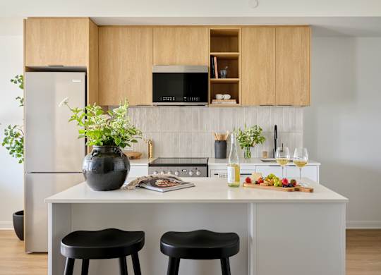 A kitchen with a white countertop and black stools.