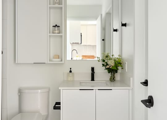 A white bathroom with a toilet, sink, and mirror.