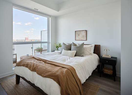 A bedroom with a large bed and a view of the city.