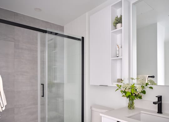 A modern bathroom with a toilet, sink, and a glass shower door.