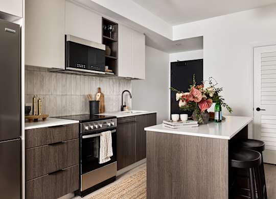 A modern kitchen with a stainless steel refrigerator and a wooden island.