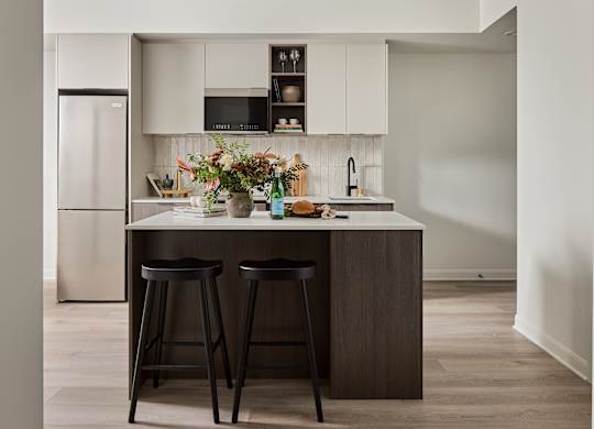 A kitchen with a white countertop and black bar stools.