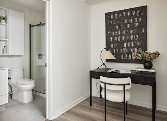 A bathroom with a toilet and a desk with a chair.