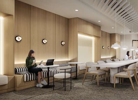 A woman is sitting on a bench in a room with wooden walls and a long table with chairs.