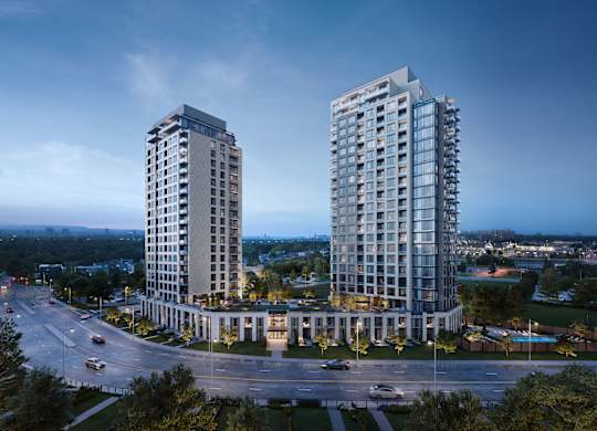 Two modern high-rise buildings are situated in a roundabout with a road and cars passing by.